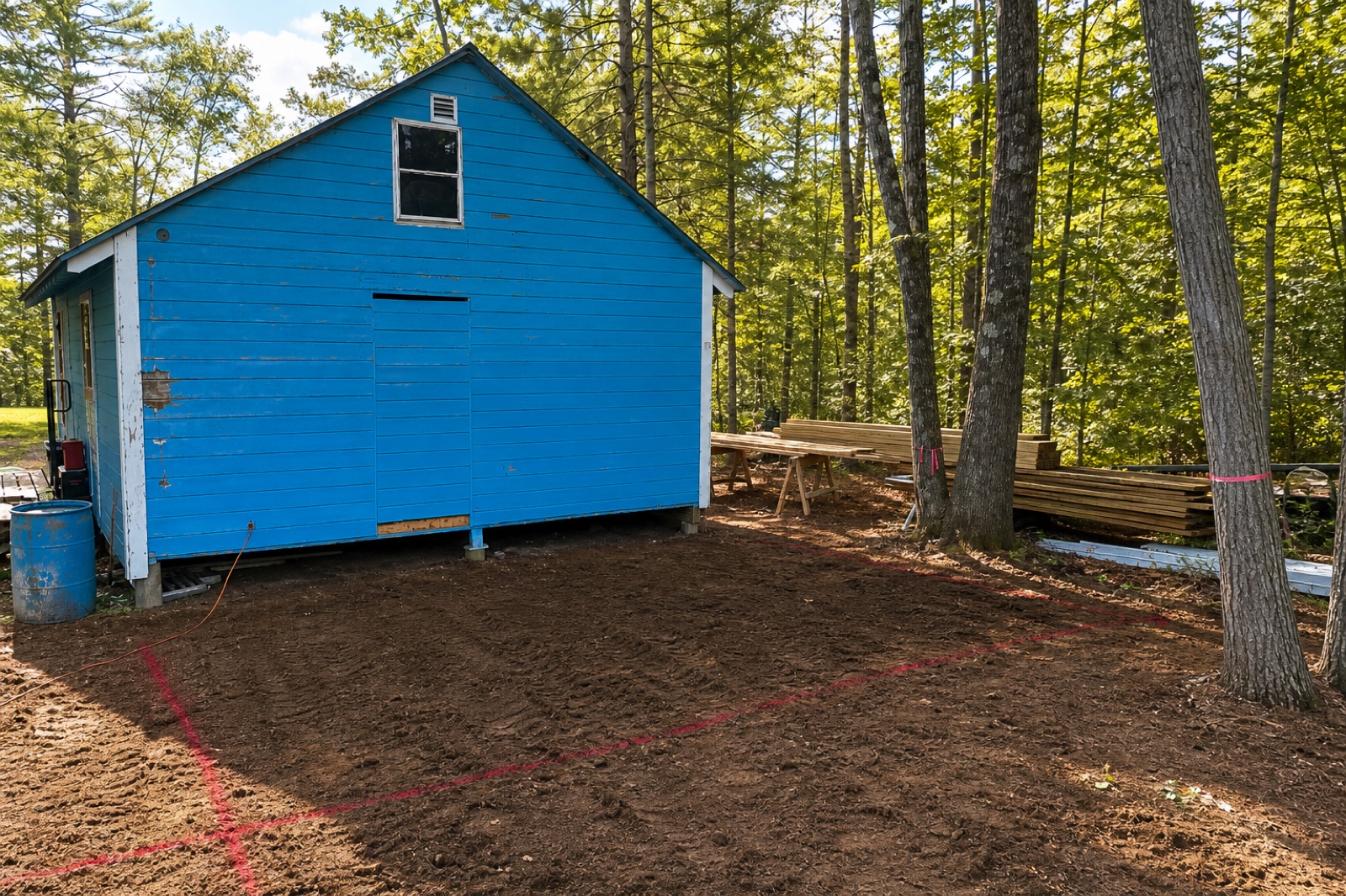 Blue cabin with red spray-paint layout lines marking the next build footprint